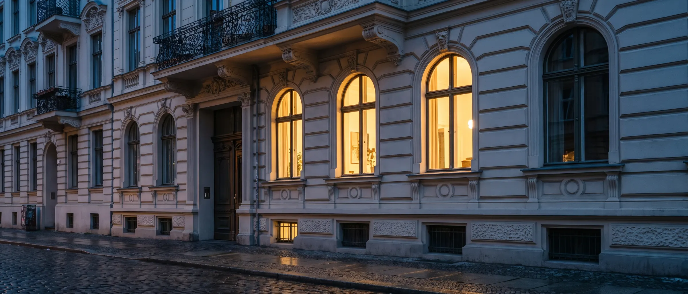 Sanierte Gründerzeitfassade am Abend, warm erleuchtete Fenster